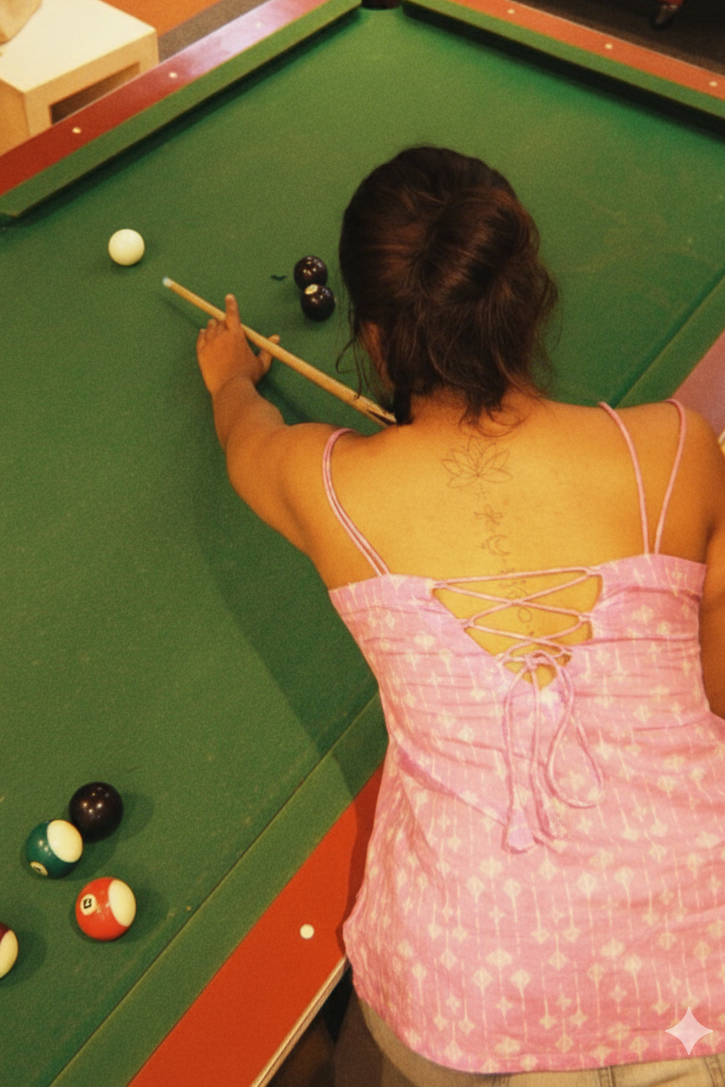 Woman playing pool at a green pool table with cues and balls.