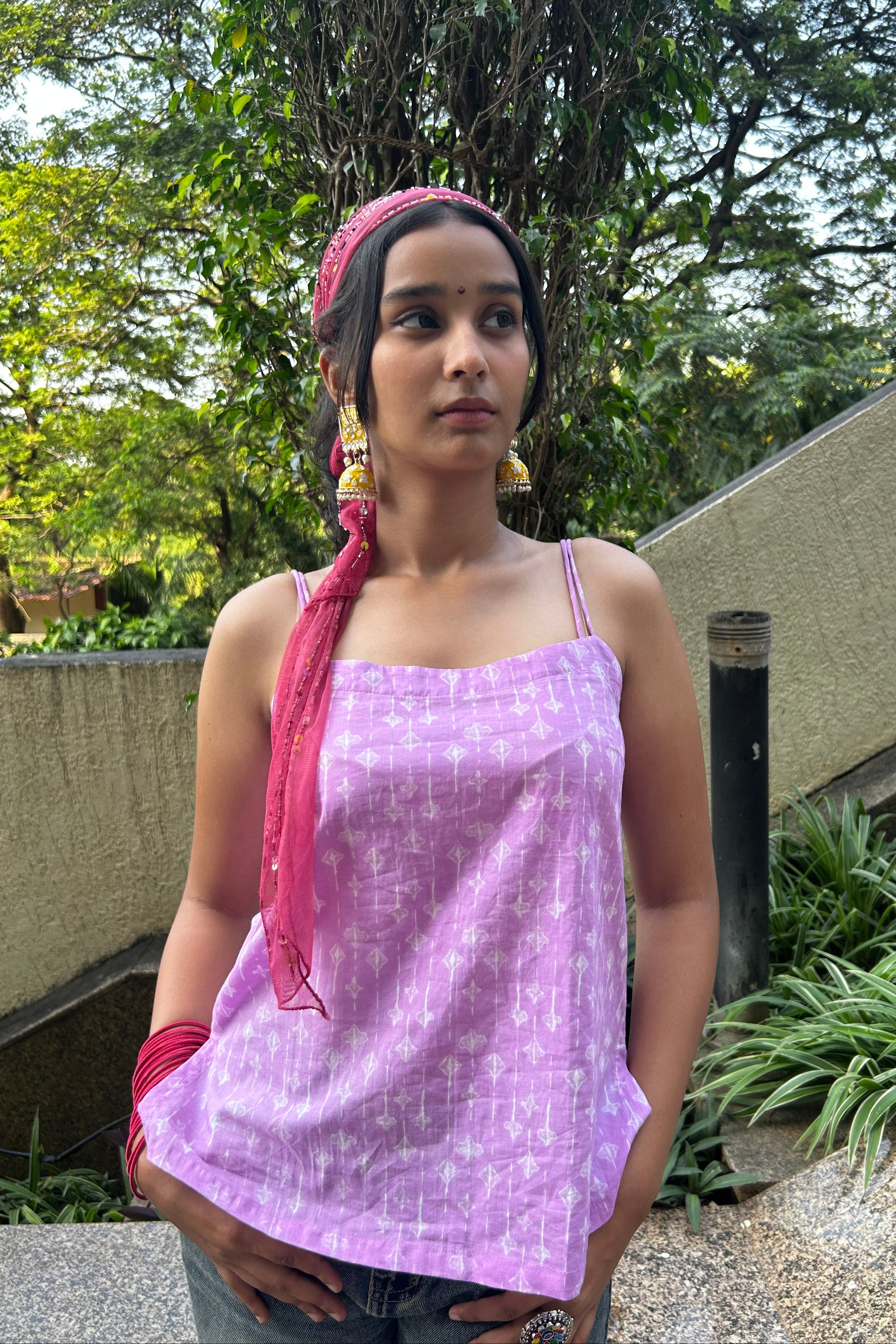 Woman wearing a purple top with a pink scarf in an outdoor setting