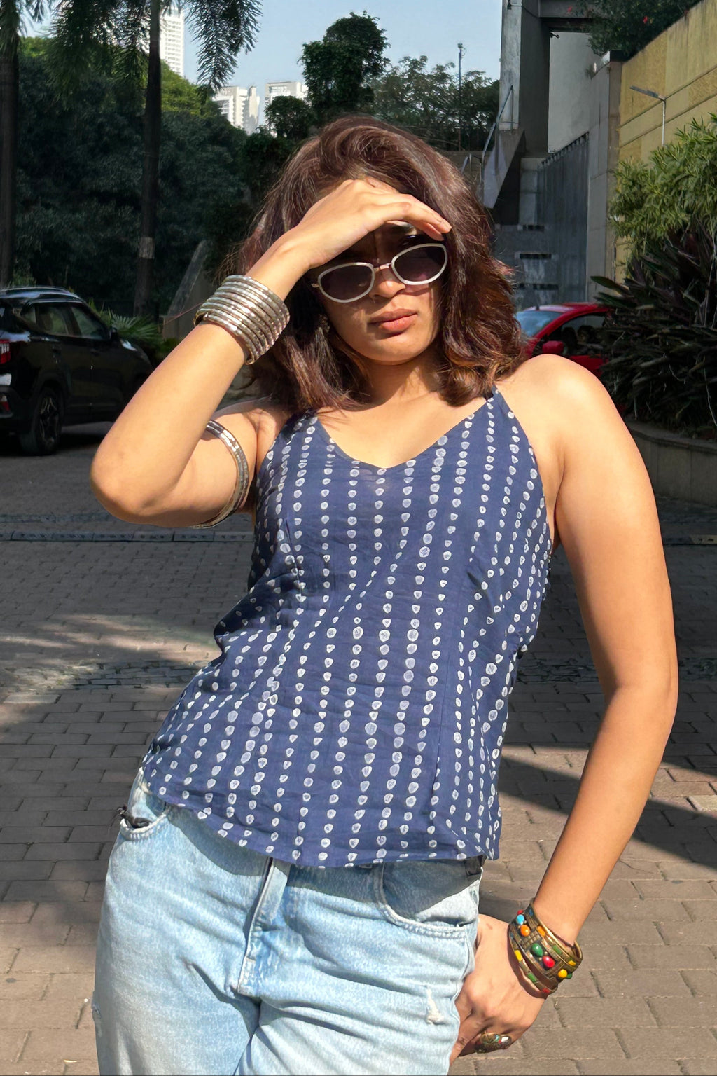 Woman wearing a blue patterned top and sunglasses outdoors.