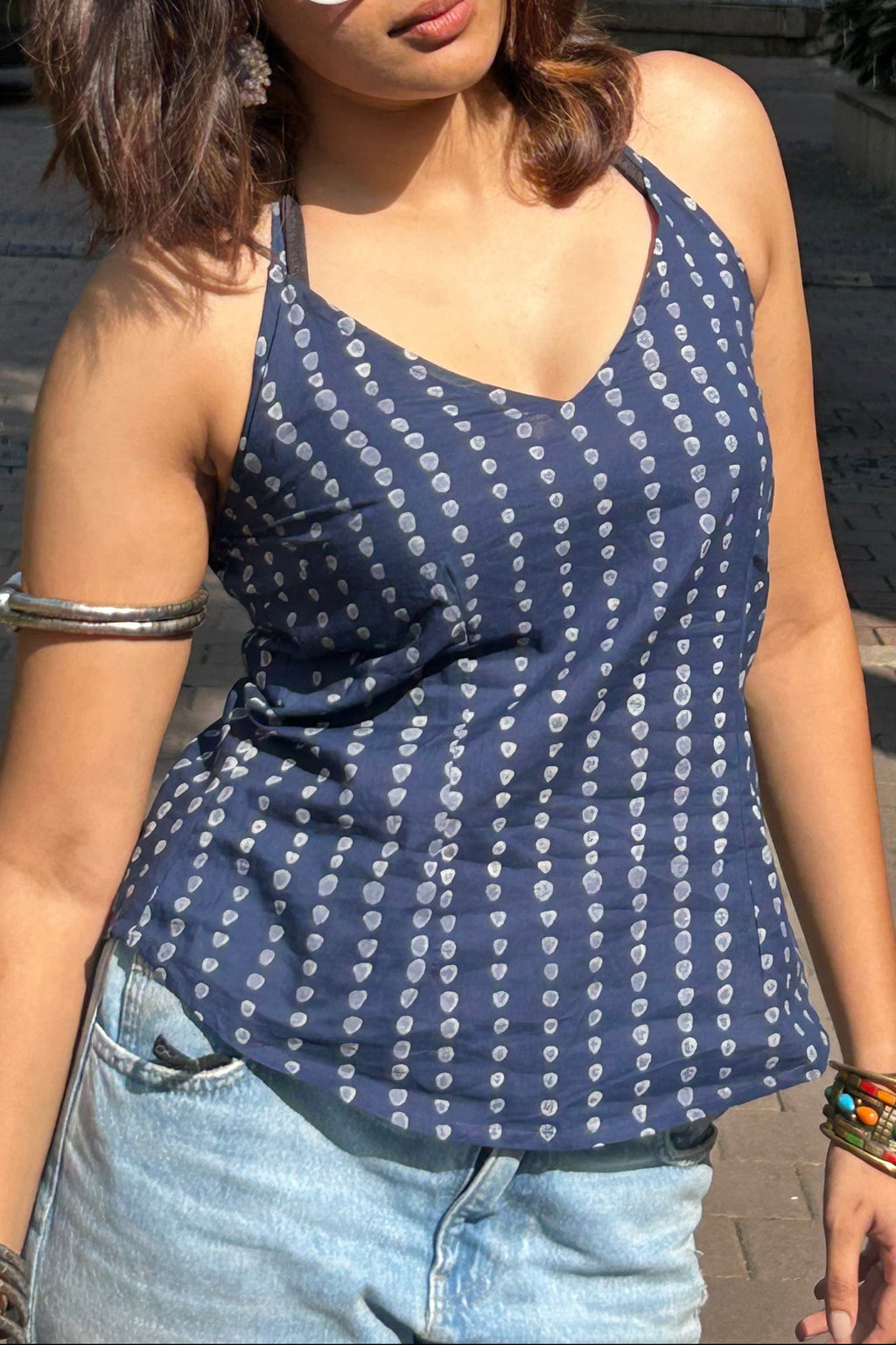 Woman wearing a blue patterned top and sunglasses outdoors