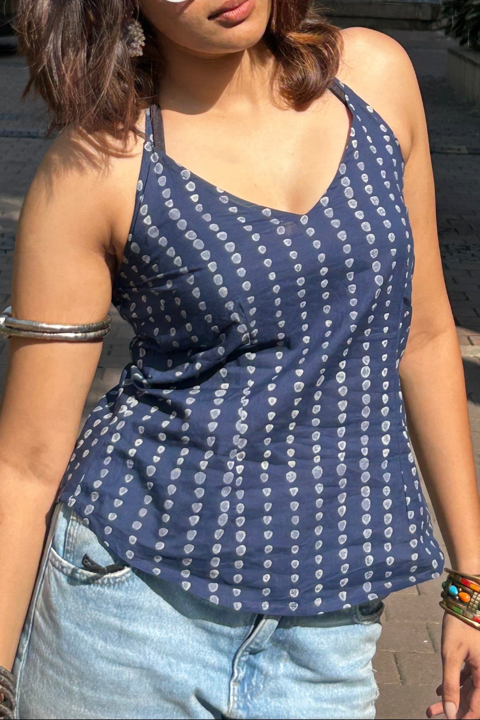 Woman wearing a blue patterned top and sunglasses outdoors