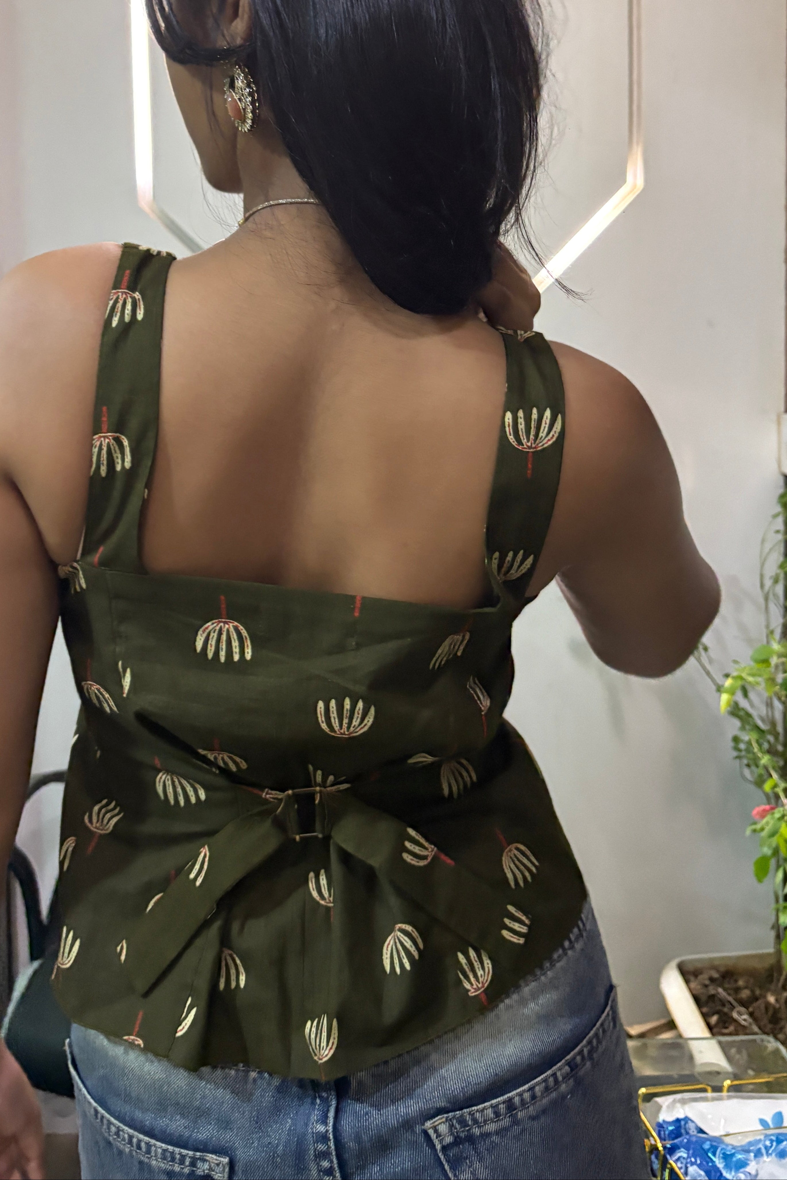 Person wearing a green dress with a pattern, standing on a reflective surface.